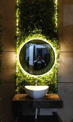 a bathroom with a round mirror on the wall and plants growing up to it's sides