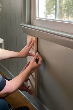 a woman is working on a wall with a screwdriver in front of her