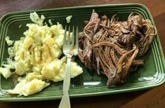 a green plate topped with meat and mashed potatoes