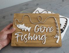 a wooden sign that says gone fishing with fish on it and some string attached to it