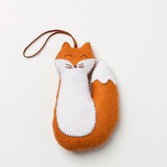 an orange and white cat ornament hanging from a cord on a white surface