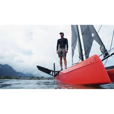 a man standing on top of a red boat in the water