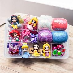 a plastic container filled with lots of little princess figurines on top of a wooden table