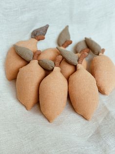 several pieces of felt sitting on top of a white cloth covered tablecloth with leaves attached to them