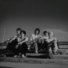 black and white photograph of four women sitting on steps with skateboards in front of them