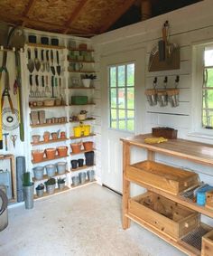 a room with many pots and pans on the wall, shelves filled with utensils