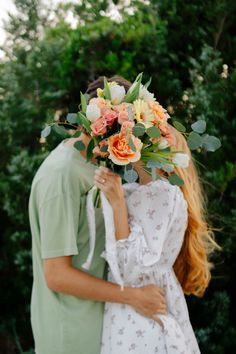 two people standing next to each other with flowers in their hair and one person holding the woman's head