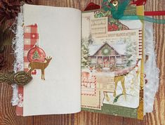 an open christmas card book on a wooden table with ornaments and ribbon around it,