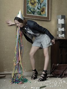 a woman in a party hat leaning against a wall with confetti on it