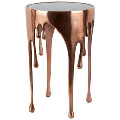 a table that has some kind of dripping liquid on it's side and is made out of copper colored metal