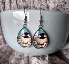 Black Capped Chickadee Among Flowers Painting Inspired Earrings Artistic, attractive bold statement earrings, a perfect gift and choice for nature and bird lovers for any occasion. Ideal gift for an artist. Measures 0.98 inches in length and 0.70 inches in width. Comes with First Class Free shipping. Colors may vary due to monitor and lighting differences. Dangle Earrings With Bird Design For Gift, Whimsical Bird Design Earrings For Gift, Black Capped Chickadee, Flowers Earrings, Broken Arrow, Gifts For An Artist, Black Cap, Gift Jewelry, Fun Earrings