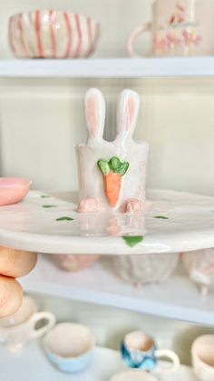 a person holding a plate with a small rabbit figurine on it