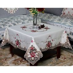 a white table cloth with red flowers in a vase on it and two couches