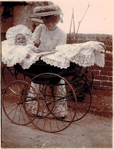 an old photo of a woman holding a baby in a stroller with the child's head resting on it