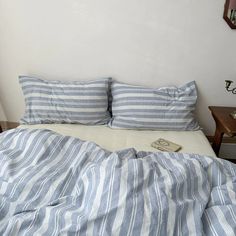 an unmade bed with blue and white striped sheets