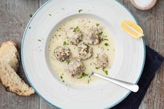 a white plate topped with meatballs covered in gravy next to a piece of bread