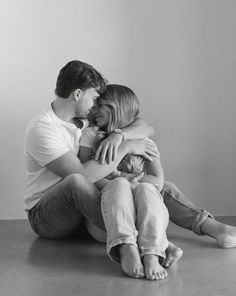 a man and woman sitting on the floor with their arms around each other as they hug