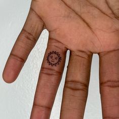 a person's hand with a small sun tattoo on their left thumb and finger