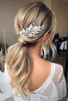 a woman with blonde hair in a ponytail wearing a bridal headpiece made of flowers