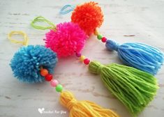 several colorful pom poms are arranged on a white surface with beaded beads