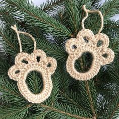 two crocheted christmas ornaments hanging from a pine tree with the shape of a baby's boot