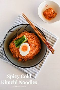 a bowl with noodles and an egg in it on a table next to chopsticks