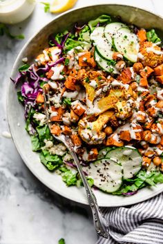 a bowl filled with salad and dressing on top of a white table cloth next to a fork