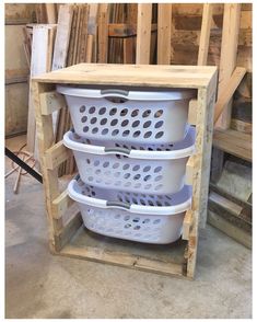 three white baskets stacked on top of each other in a storage area with wood pallets