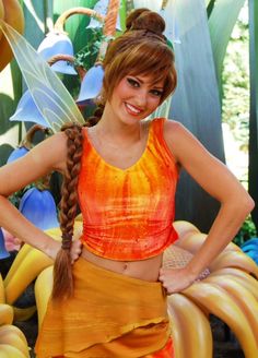 a woman in an orange and yellow costume standing with her hands on her hips, smiling at the camera