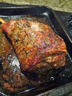 a piece of meat is being cooked in a pan with a wooden spoon on the side