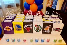 there are many bags on the table and balloons in the air above them, all decorated with different sports logos