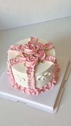 a white cake with pink flowers and pearls on it's side sitting on a table