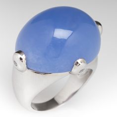 This wonderful ring is centered with an oval, blue chalcedony cabochon, weighing 30.00 carats, set in a four-prong setting. Each prong is flush set with one (1) round brilliant cut diamond. The ring measures 19.7mm at the top, rises 12.8mm above the finger, tapering to 3.4mm wide and 0.9mm thick at the base of the shank. This ring is currently a size 6.5. Luxury Blue Cabochons For Anniversary, Luxury Blue Round Cabochons, Classic Blue Cabochons For Formal Occasion, Blue Classic Cabochons For Formal Occasion, Blue Formal Classic Cabochons, Blue Classic Formal Cabochons, Oval Cabochon Fine Jewelry With Polished Finish, Polished Oval Cabochon Fine Jewelry, Luxury Polished Moonstone Ring With Oval Cabochon