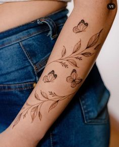 a woman's arm with flowers and butterflies tattooed on the side of her arm