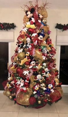 a christmas tree decorated with mickey mouse and other disney characters in red, gold and silver