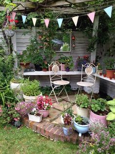 an outdoor garden with potted plants and chairs