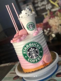 there is a starbucks cake with pink frosting on the top and two drinks on top