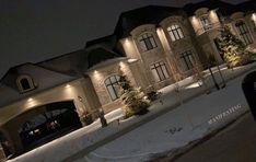 a large house is lit up at night in the snow