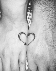 two people with tattoos on their hands holding each other's hand and one has a heart in the middle