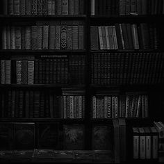 a bookshelf filled with lots of black and white books in the dark room