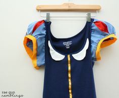 a blue and yellow dress hanging on a wooden hanger next to a white wall