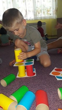 a young boy playing with toys on the floor in front of other children sitting around