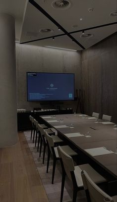 a long table with chairs and a flat screen tv on the wall in a conference room