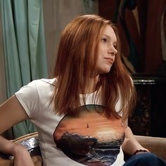 a woman sitting in a chair with a t - shirt that has an image of a bird on it