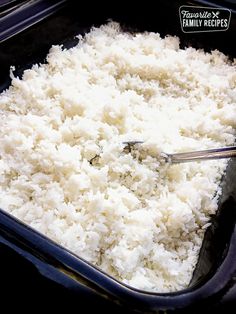 rice is being cooked in a black casserole dish with a spatula on the side