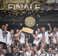 a group of men standing next to each other in front of a crowd holding up a trophy