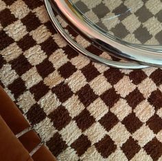 a close up of a glass table on a checkered rug with a metal frame