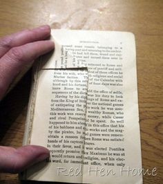 a person holding an open book on top of a wooden table