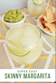 two glasses filled with drinks sitting on top of a table next to chips and guacamole