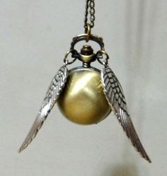 a gold ball with two wings hanging from it's side and a chain attached to it